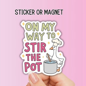 May include: A sticker or magnet with the text "ON MY WAY TO STIR THE POT". The design features a cartoon goose wearing a chef's hat, stirring a pot. The sticker has a white border and star accents.