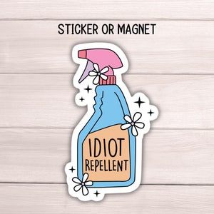 May include: A white sticker or magnet with a blue and pink cartoon spray bottle that says "Idiot Repellent".