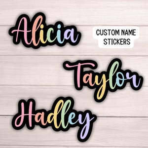 May include: Three custom name stickers with rainbow lettering. The names are Alicia, Taylor, and Hadley. The stickers are on a wood background. CUSTOM NAME STICKERS is written on a white rectangle.