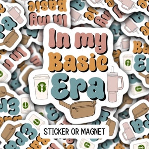 May include: A sticker or magnet with the text "In my Basic Era" in a retro font. The design features a brown fanny pack, a pink tumbler, and a white coffee cup with a green logo.
