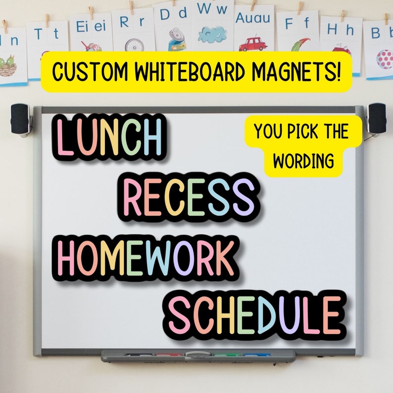 Op de afbeelding: Een wit whiteboard met kleurrijke magnetische woorden die "Lunch", "Recess", "Homework" en "Schedule" zeggen. De woorden zijn in een regenboogkleurenschema. Een gele banner bovenaan zegt "Custom Whiteboard Magnets!" en een kleinere gele banner zegt "You Pick The Wording".