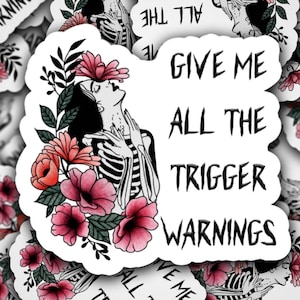 May include: A sticker with a black and white illustration of a skeleton with flowers. The text on the sticker reads "Give me all the trigger warnings".