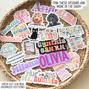 May include: A collection of colorful stickers with various designs, including names, phrases, and illustrations. The stickers are arranged on a woven basket surface. Some of the stickers feature floral designs, while others have a retro 70s aesthetic. The text on the stickers includes "In My Dance", "Drink Your Water You Dehydrated", "What?", "When I Die Delete My Kindle History", "Cynthia BSN RN", "Olivia", "Mama", "Mommy Mom", "Ms. Zubieta", and more.