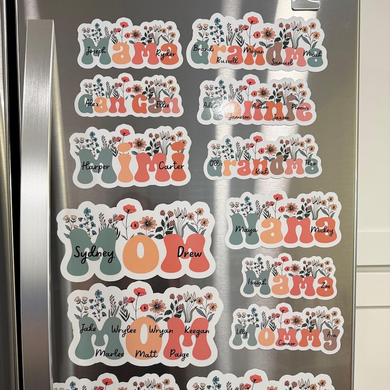 May include: A collection of floral-themed refrigerator magnets. Each magnet features a name, such as "Mama" or "Grandma", in a stylized font, with a vase of flowers. The color palette includes orange, green, and white.