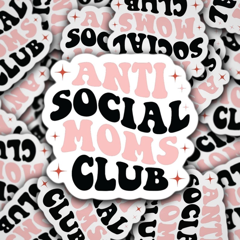 May include: A close-up of a sticker with the text "Anti Social Moms Club" in black and pink letters with a white background. The sticker has a retro style font and is surrounded by other stickers with similar designs.