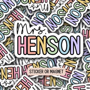 May include: A colorful sticker or magnet with the text "Mrs. Henson" in rainbow colors. The sticker is surrounded by other stickers with the same text in different colors.