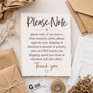 May include: A cream-colored card with the text "Please Note" in a handwritten font. The card includes a message about upgrading shipping for time-sensitive orders. The card is surrounded by packaging materials and stationery.