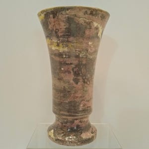 May include: A tall, handcrafted vase with a flared top and a rounded base. The vase features a marbled design in shades of pink, brown, and yellow. The ceramic vase is a decorative item for the home.
