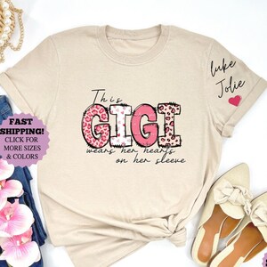 Dieses Gigi trägt ihr Herz auf ihrem Ärmelhemd, benutzerdefiniertes Gigi-Shirt mit Kindernamen, Gigi-T-Shirt, Muttertagsgeschenk, genannt Gigi-T-Stück (Mondzeit-Schrift)