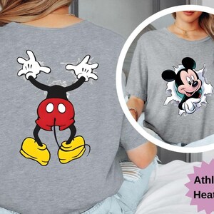 Puede incluir: Camiseta gris jaspeado atl&eacute;tico con un dise&ntilde;o de dibujos animados de Mickey Mouse. La parte delantera muestra a Mickey saliendo por un agujero, mientras que la parte trasera muestra el cuerpo y los brazos de Mickey. El dise&ntilde;o incluye pantalones cortos rojos, zapatos amarillos y guantes blancos.