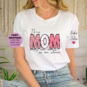 Diese Mutter trägt ihr Herz auf ihrem Ärmelhemd, benutzerdefiniertes Muttershirt mit Kindernamen, Mutter-T-Shirt, Muttertagsgeschenk, benannte Mutter Hemd (Mondzeitschrift)
