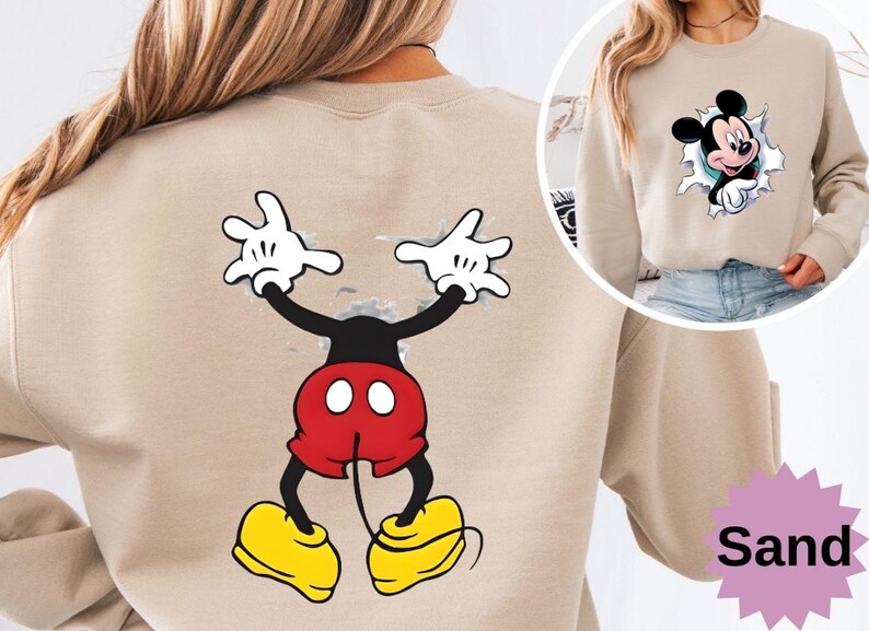 Puede incluir: Sudadera color arena con un gr&aacute;fico de Mickey Mouse. La parte delantera muestra a Mickey rompiendo un efecto de papel rasgado, mientras que la parte trasera muestra una imagen de cuerpo completo de Mickey Mouse con los brazos levantados. La sudadera tiene cuello redondo.