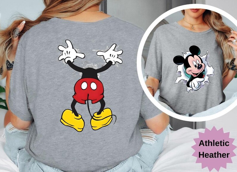 Puede incluir: Camiseta gris jaspeado atl&eacute;tico con un dise&ntilde;o de dibujos animados de Mickey Mouse. La parte delantera muestra a Mickey saliendo por un agujero, mientras que la parte trasera muestra el cuerpo y los brazos de Mickey. El dise&ntilde;o incluye pantalones cortos rojos, zapatos amarillos y guantes blancos.