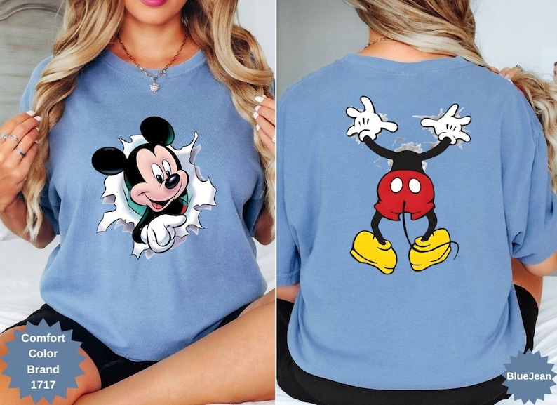Peut inclure: T-shirt bleu clair avec Mickey Mouse. Le motif avant montre Mickey per&ccedil;ant un fond d&eacute;chir&eacute;, tandis que le dos affiche Mickey les bras lev&eacute;s. Le t-shirt porte les textes "Comfort Color Brand 1717" et "BlueJean".