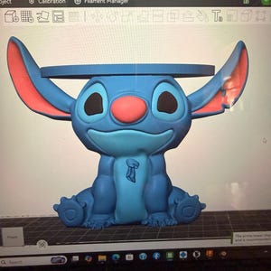 Könnte beinhalten: Ein digitales 3D-Modell der Figur Stitch auf einem Computerbildschirm. Die Figur ist blau, hat große Ohren mit rosa Innenseiten, eine runde rosa Nase und schwarze Augen. Auf dem Kopf der Figur befindet sich eine flache, kreisförmige Plattform.