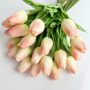 May include: A bouquet of 20 artificial pink tulips with green stems and leaves. The tulips are arranged in a circular shape.