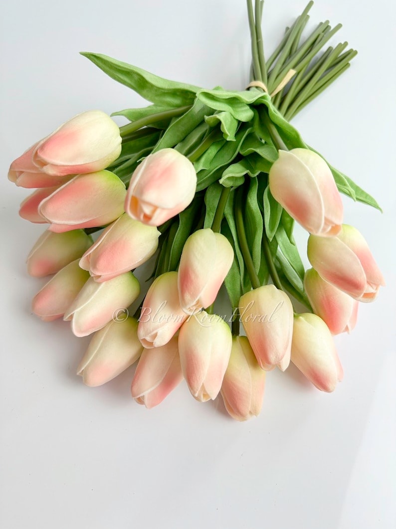 May include: A bouquet of 20 artificial pink tulips with green stems and leaves. The tulips are arranged in a circular shape.