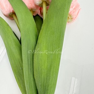 May include: A bouquet of pink artificial tulips with green stems and leaves.