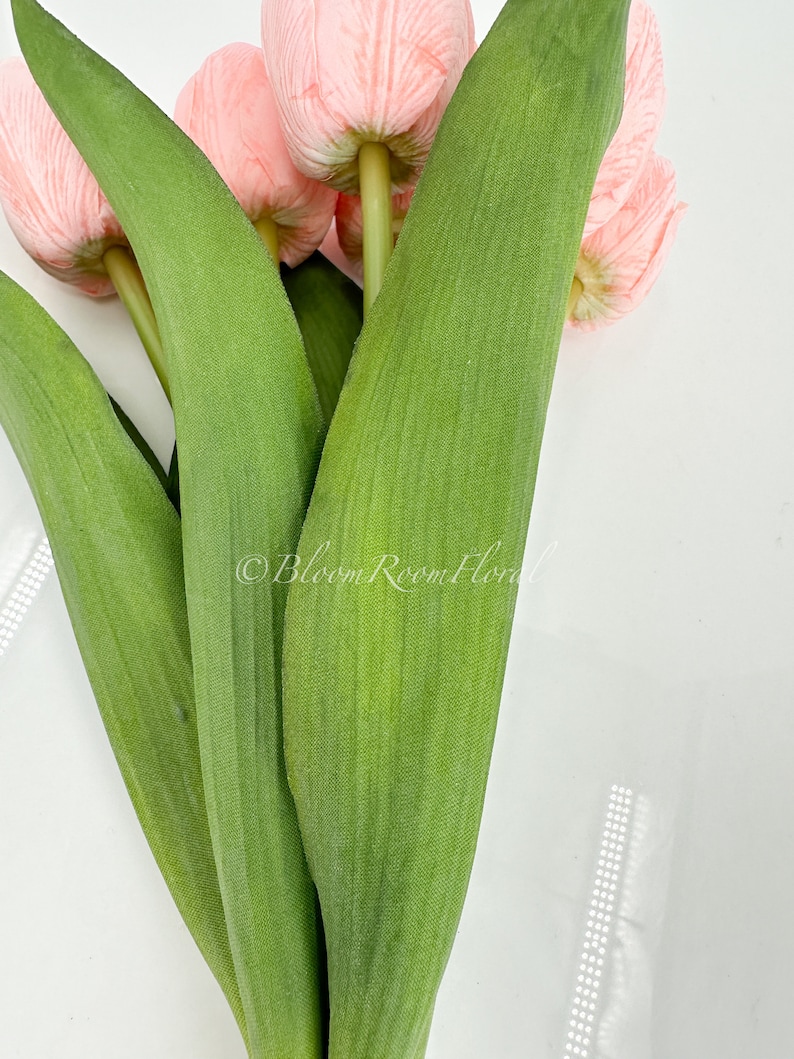 May include: A bouquet of pink artificial tulips with green stems and leaves.