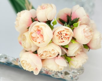 Puede incluir: Un ramo de flores artificiales de color rosa pálido con tallos verdes. Las flores están dispuestas en un racimo y tienen un aspecto delicado y romántico.
