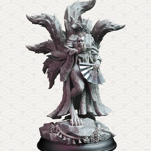 Puede incluir: Una escultura gris y detallada de un kitsune, un espíritu de zorro de nueve colas, que lleva un kimono japonés tradicional y sostiene un abanico. La escultura está sobre una base de piedra gris.