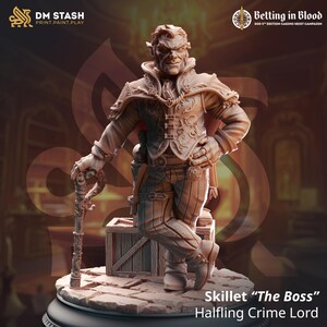Puede incluir: Una figura miniatura pintada de un señor del crimen halfling, Skillet "The Boss", que lleva un traje marrón y sostiene un bastón. La figura está de pie sobre una base circular con una textura de piedra.