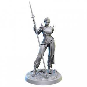 May include: A gray, detailed miniature figurine of a female warrior holding a spear. She is wearing a leather skirt, a belt with pouches, and a leather bra with a decorative design. The figurine is standing on a round base.