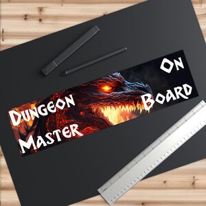 Puede incluir: Una cabeza de dragón roja y naranja con un ojo brillante y llamas en su boca. El texto "Dungeon Master" está en el lado izquierdo de la imagen y "ON BOARD" está en el lado derecho.