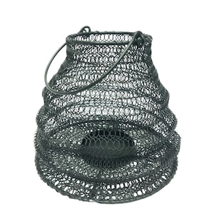 May include: A black metal candle lantern with a wire mesh design and a handle. The lantern has a round shape and is designed to hold a candle.
