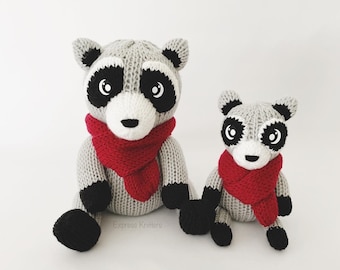 Puede incluir: Dos juguetes de mapache tejidos con bufandas rojas. El mapache más grande está sentado con las piernas cruzadas, mientras que el mapache más pequeño está sentado con las piernas estiradas. Ambos mapaches tienen ojos y narices negros, y pelaje blanco en la cara.