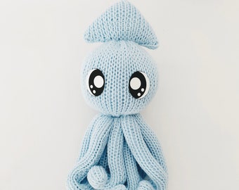 Puede incluir: Un juguete de pulpo de punto azul claro con grandes ojos negros. El pulpo tiene una cabeza puntiaguda y ocho tentáculos.