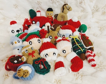 Op de afbeelding: Een verzameling van gehaakte kerstversieringen, waaronder een sneeuwpop, de kerstman, een peperkoekman, een rendier, een sok, een krans en een paardenslee.