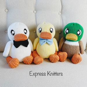 May include: Three knitted duck plushies, one white with a black bow tie, one yellow with a blue bow tie, and one green with a brown and white striped body. The ducks are sitting on a light brown couch. The text "Express Knitters" and "Knitting Machine Pattern PDF Only" is below the ducks.