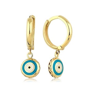 May include: Gold hoop earrings with a dangling blue and white evil eye charm. The charm has a gold rim and a white circle in the center with a black dot.