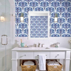 May include: A bathroom vanity with a white countertop, drawers, and wicker baskets. The wall features a blue and white floral wallpaper. A mirror hangs above the sink, reflecting the wallpaper pattern. The room has a clean, modern aesthetic.