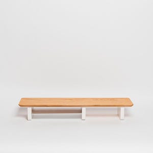 May include: A rectangular wooden shelf featuring a natural light brown wood grain top surface with rounded corners. The shelf is supported by three vertical white legs positioned along the underside, providing a stable base for the horizontal platform.