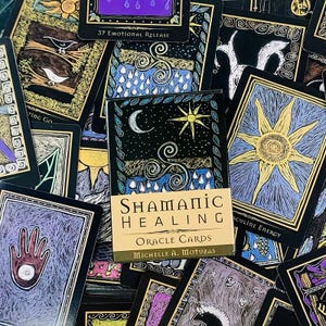 May include: A deck of Shamanic Healing Oracle Cards by Michelle A. Motuzas featuring a central box with a crescent moon, sun, and spiral design, surrounded by various illustrated cards with black borders, gold accents, and diverse symbolic imagery.