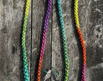 Könnte beinhalten: Ein geflochtenes Regenbogen-Seil mit einem silbernen Clip an jedem Ende. Das Seil besteht aus mehreren Farben, darunter Rot, Orange, Gelb, Grün, Blau und Lila.