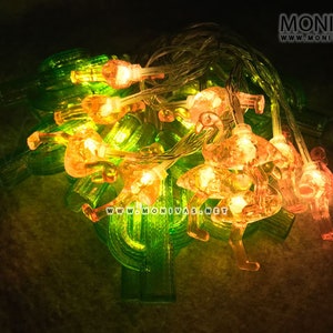 May include: String of fairy lights with clear bulbs and pink flamingo shaped holders. The lights are strung on green wire.