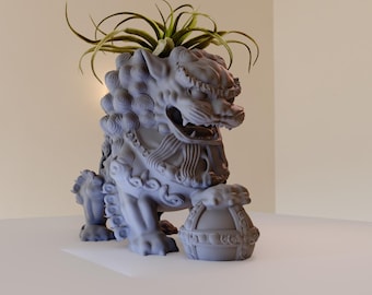 May include: A gray stone lion statue with intricate details, holding a round orb in its paws. The lion is decorated with a leafy green plant growing from its head.