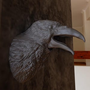 May include: A close-up of a grey raven sculpture with its beak open, mounted on a dark brown wooden surface.