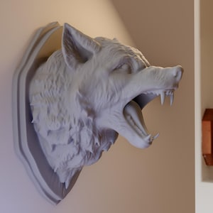 May include: A white plaster wolf's head mounted on a wall. The wolf's mouth is open and its teeth are visible. The wolf's fur is sculpted in detail.
