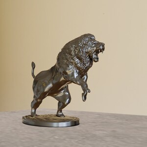 May include: A silver metal sculpture of a lion roaring with its mouth open. The lion is standing on its hind legs with its front paws raised. The sculpture is on a round base.