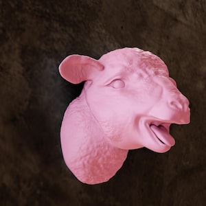 Könnte beinhalten: Eine rosafarbene Schafskopfskulptur mit offenem Mund und herausgestreckter Zunge. Die Skulptur ist an einer Wand befestigt.