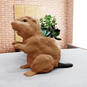 Puede incluir: Un macetero de cerámica marrón con forma de castor con cola negra. El macetero está lleno de suculentas verdes.