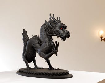 May include: A black dragon statue with red eyes, standing on a black base with a decorative border. The dragon is posed with its head turned to the side and its claws extended.