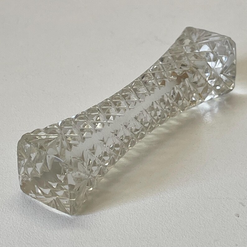 May include: A clear glass chopstick rest with a diamond pattern.