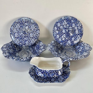Puede incluir: Un juego de vajilla con estampado floral azul y blanco. El juego incluye dos cuencos con platos a juego y una salsera con un platillo a juego. El estampado floral es un diseño clásico.