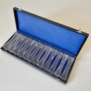 May include: A set of 12 clear glass chopsticks in a black box with a blue velvet lining.