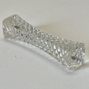May include: A clear glass paperweight with a diamond pattern.
